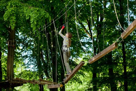 Kyiv, Ukraine- May 15, 2019 Girl in climbing gear on a rope park background . Rope park with obstacles and mountaineering. Extreme rest and summer activities concept.のeditorial素材