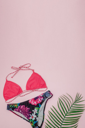 Hat, swimsuit, sunglasses on pink background. Top view, flat lay, space for textの写真素材