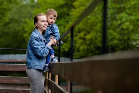 Happy young mother playing and having fun with her little baby son on warm spring or summer day in the park. Happy family concept, mother's day.の写真素材