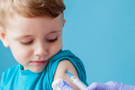 Vaccination concept. Female doctor vaccinating cute little boy on blue background, closeup.