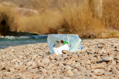 River pollution near the shore, garbage near the river, plastic food waste, contributing to...