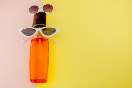 Bottle sunblock on bright square yellow and pink background. The concept of the resort at sea, summer time. Top view, flat lay, minimalism, copy space.の写真素材
