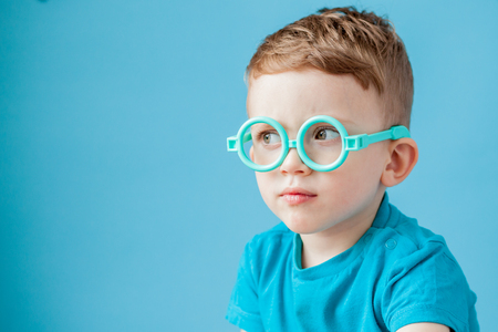 Portrait of a little boy in toy glasses on blue background.の写真素材