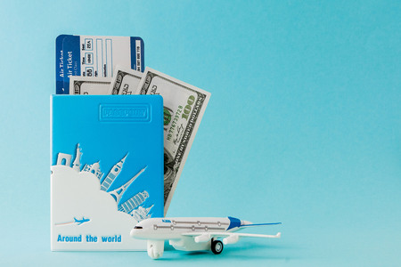 Passport, dollars, plane and air ticket on a blue background. Travel concept, copy space.の写真素材