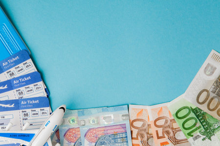 Passport, dollars and euro, plane and air ticket on a blue background. Travel concept, copy space.