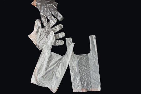 Plastic bag with handles, gloves, on a black background . Used plastic bag for recycling. Concept -...