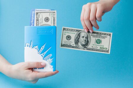 Passport, dollars and air ticket in woman hand on a blue background. Travel concept, copy spaceの写真素材