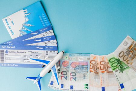 Passport, dollars and euro, plane and air ticket on a blue background. Travel concept, copy space.の写真素材