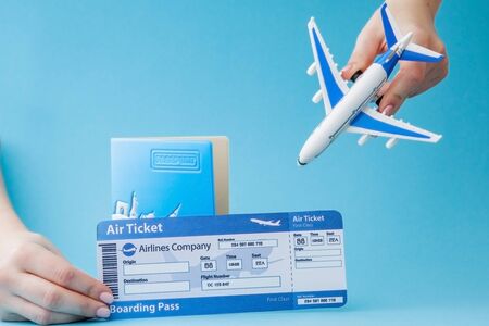 Passport, plane and air ticket in woman hand on a blue background. Travel concept, copy space.の写真素材