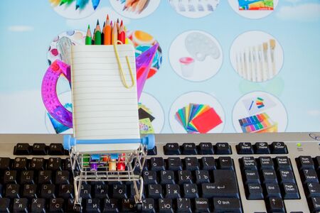 Shopping cart full of school tools on the keyboard, online shopping concept.の写真素材