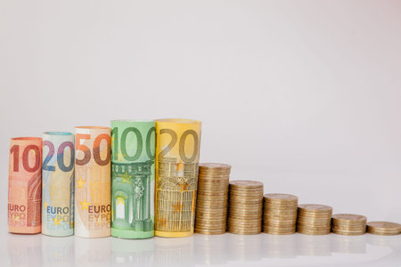 Ten, twenty, fifty, one hundred, two hundred and coins euro rolled bills banknotes on white...