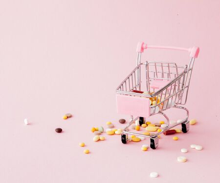 Shopping trolley from the supermarket full of pills and drugs on a pink background. Purchases of medical preparations, purchase on the Internet. Flat lay, top view.の写真素材