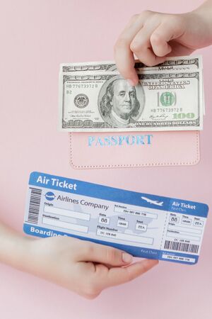 Passport, dollars and air ticket in woman hand on a pink background. Travel concept, copy space.の写真素材