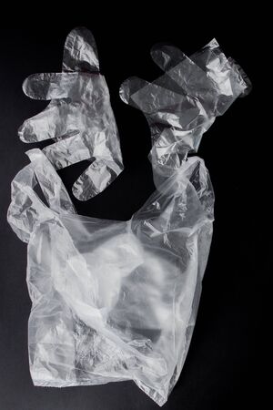Plastic bag with handles, gloves, on a black background . Used plastic bag for recycling. Concept - ecology, planet pollution with plastic cellophane polyethylene.の写真素材
