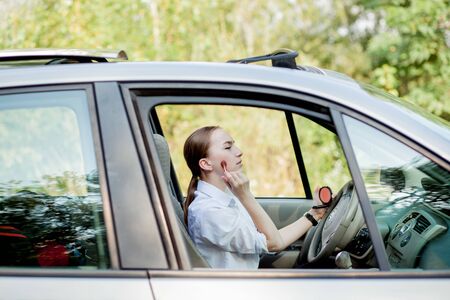 Picture of young businesswoman doing makeup while driving a car in the traffic jam.の写真素材