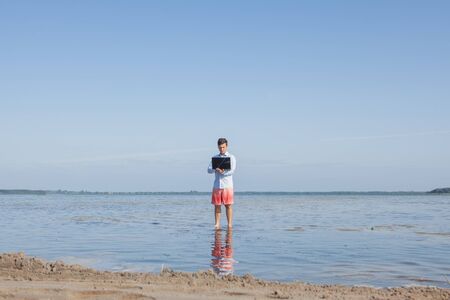 Male businessman with a laptop in the water. Freelance work concept.の写真素材