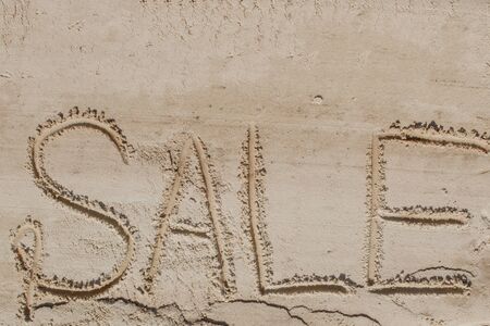 The word sale is painted on the sand. Beach background. View from above. The concept of summer, summer kanikkuly, vacation, holydaysの写真素材