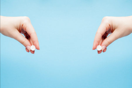 Close-up shot of pill in nurse's hand isolated over blue background.の写真素材