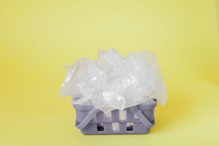 polythene bags in shopping basket on yellow background.