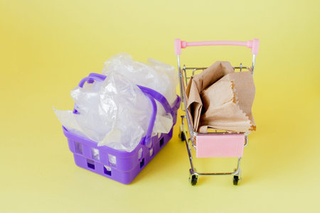 polythene and paper bags in a shopping basket on a yellow background.