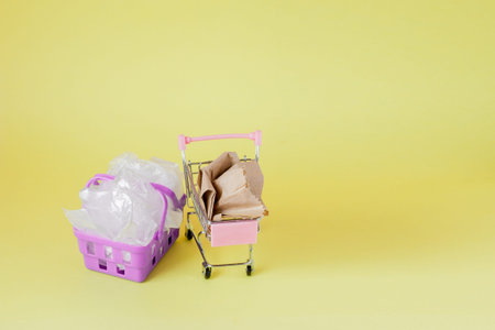 polythene and paper bags in a shopping basket on a yellow background.