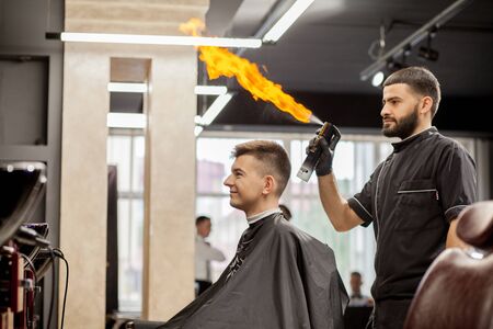 Brutal guy in modern Barber Shop. Hairdresser makes hairstyle a man . Master hairdresser does hairstyle with hair clipper. Concept barbershop.の写真素材