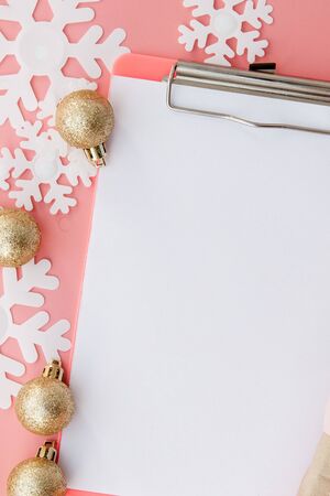 Christmas gift in women's hands and notebook on a pink background, a view from above.の写真素材