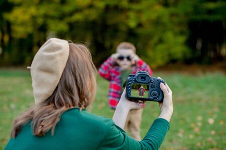 Woman photographer photographing the child to spend outside in the park.の写真素材