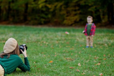 Woman photographer photographing the child to spend outside in the park.の写真素材