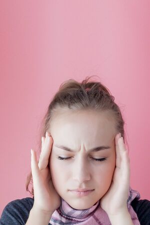 Young woman has headache, on a pink background.の写真素材