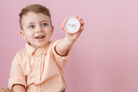 boy giving ring in box on pink background.の写真素材