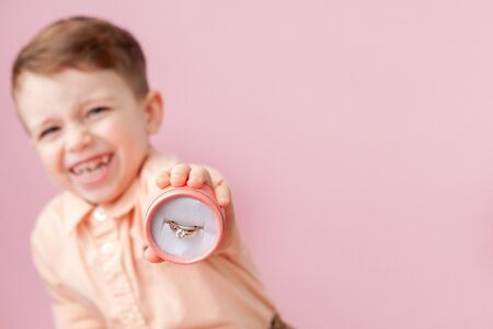 boy giving ring in box on pink background.の写真素材