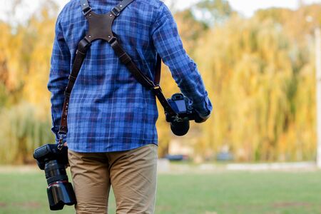 Professional photographer in action with two cameras on a shoulder straps.の写真素材