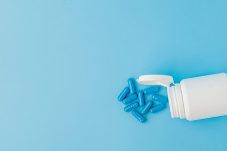 Blue capsules, pills on a blue background. Capsules in a white jar. Vitamins, nutritional...