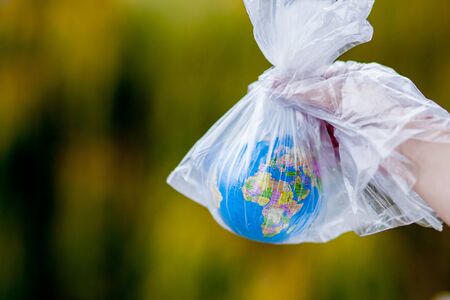 The human hand holds the planet earth in a plastic bag. The concept of pollution by plastic debris. Global warming due to greenhouse effectの写真素材