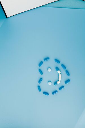 Pharmaceutical medicine pills, tablets and capsules in the shape of a heart on a blue background.の写真素材