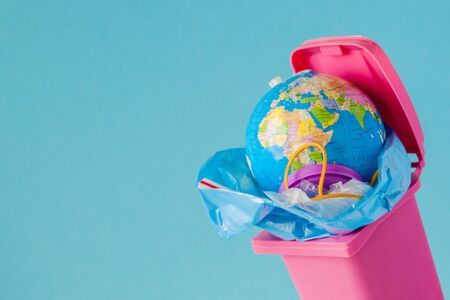 Earth globe lies in the trash. The globe lies in a heap of plastic. Plastic pollution of nature.の写真素材