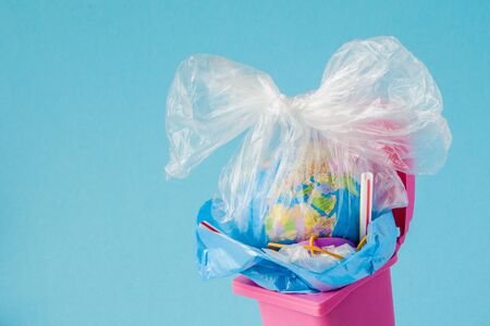 Earth globe lies in the trash. The globe lies in a heap of plastic. Plastic pollution of nature.の写真素材