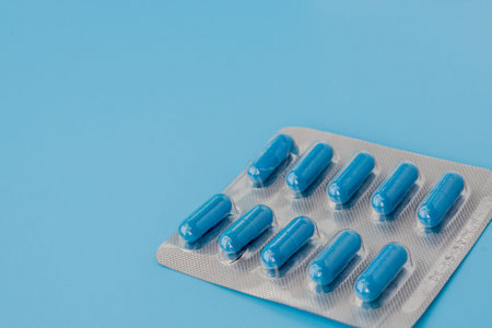 Blue capsules, pills on a blue background. Vitamins, nutritional supplements for women's health.