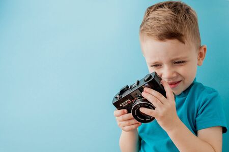 Little boy with an old camera on a blue background.の写真素材