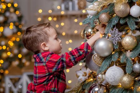 Little boy decorating Christmas tree with toy balls.の写真素材