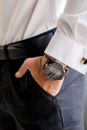 Man gets ready for work by buttoning up his business shirt. Groom's morning preparation before...