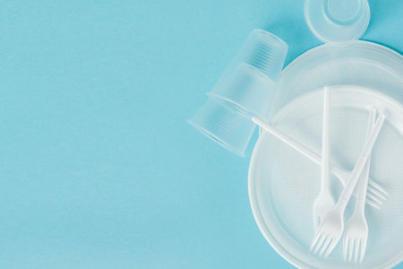 Plastic dishes on a blue background. Disposable tableware.