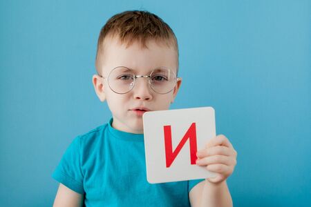 Cute little boy with letter on blue background. Child learning a letters. Alphabetの写真素材