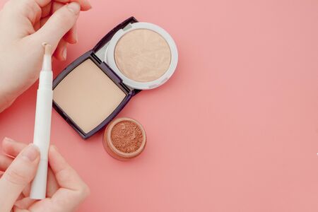 Woman's beauty blogger hands holding bottle and tube spa professional hi-end cosmetics on pink background, minimalism concept, warm cozy tones and copyspace.の写真素材