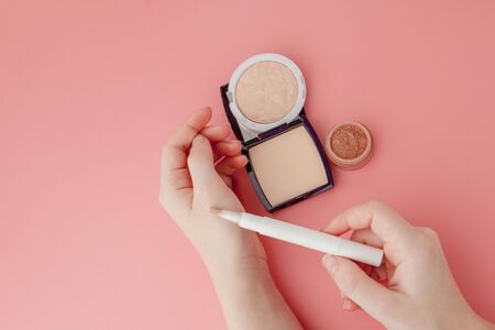 Woman's beauty blogger hands holding bottle and tube spa professional hi-end cosmetics on pink background, minimalism concept, warm cozy tones and copyspace.の写真素材