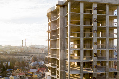 Aerial view of concrete frame of tall apartment building under construction in a city.