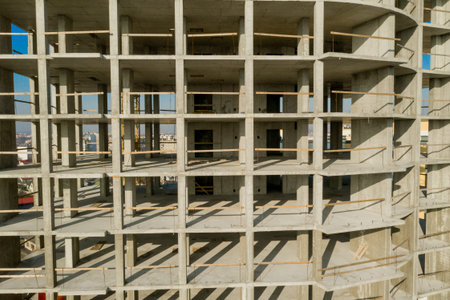 Aerial view of concrete frame of tall apartment building under construction in a city.