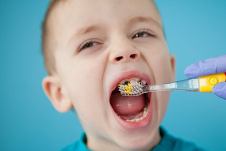 Little cute boy brushing his teeth on blue background.