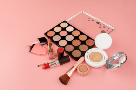 Various makeup productson pink background with copyspace.